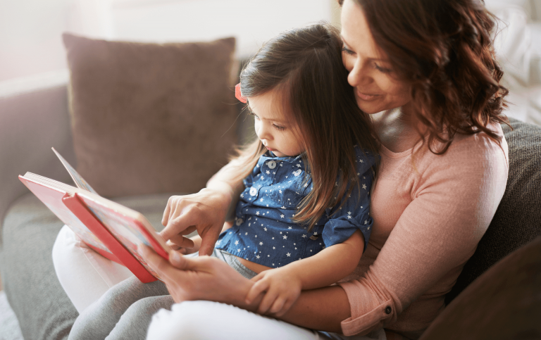 mother and daughter reading a book on the sofa